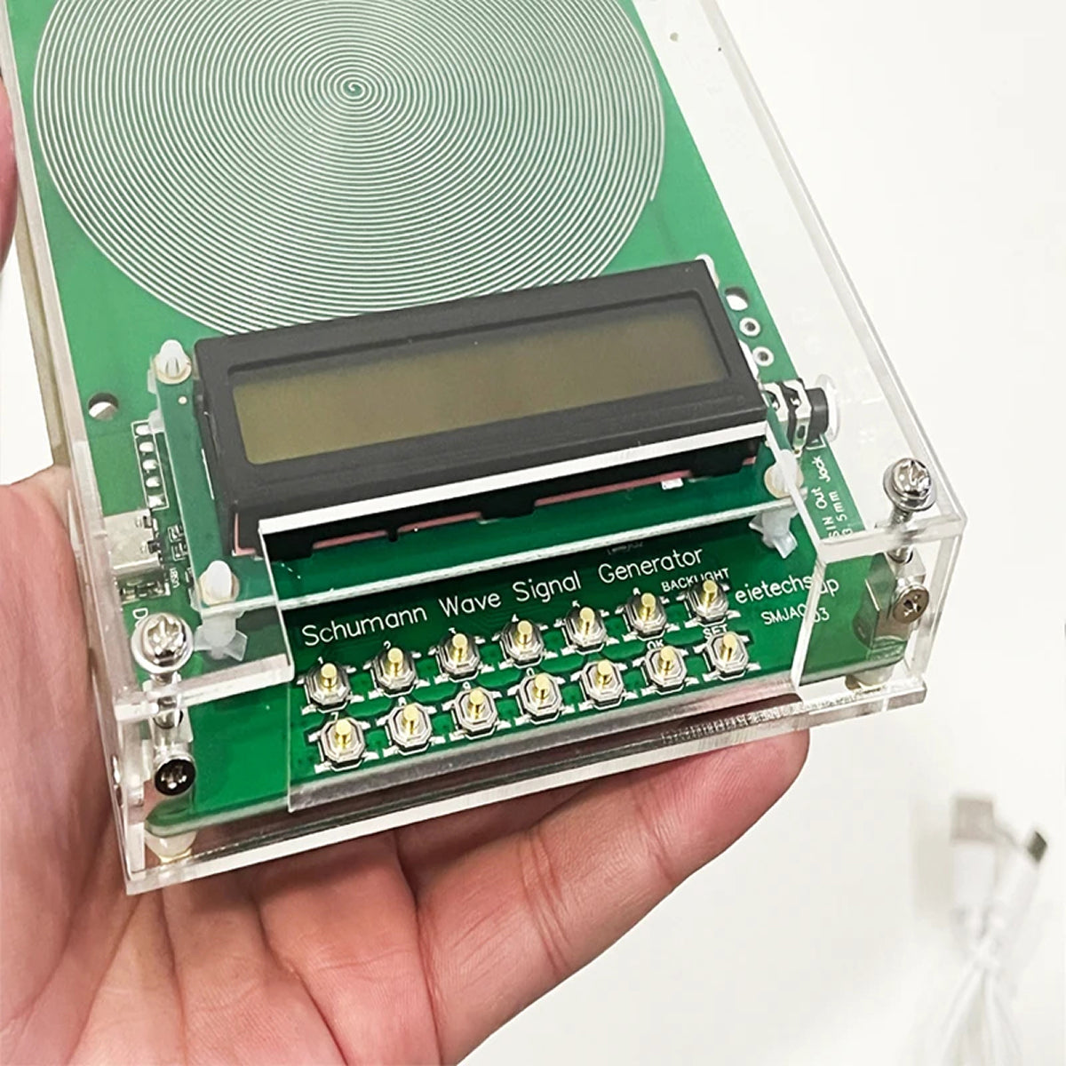 Schumann Wave Signal Generator held in a hand with a white background