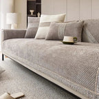 Gray sofa with cushions and a cup on a light gray rug in a room.