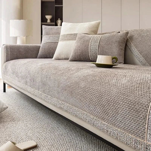 Gray sofa with cushions and a cup on a light gray rug in a room.