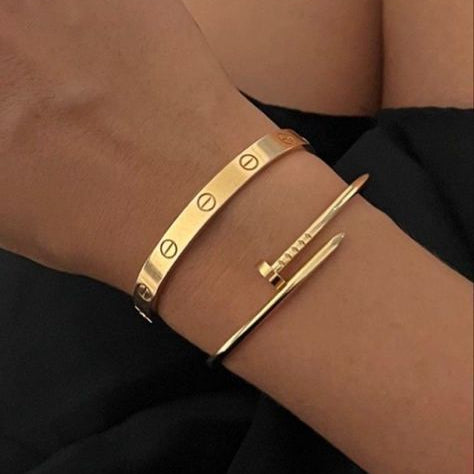 Gold bracelet with a unique design on a wrist against a black background