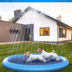 Two dogs playing in a blue inflatable sprinkler pad on a grassy area with a house in the background.