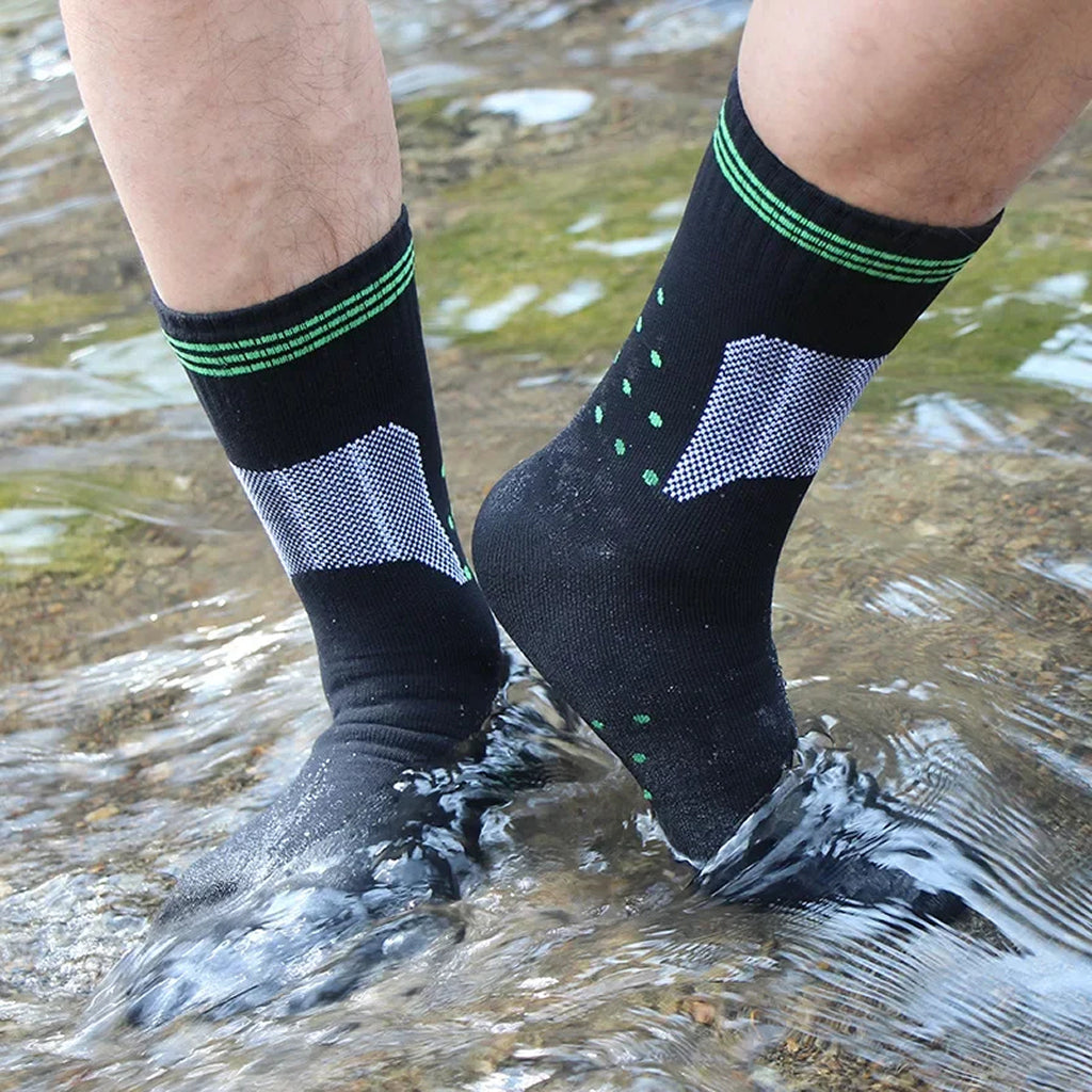 Person wearing black socks with green accents standing in water