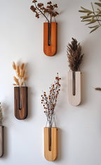 Set of wall-mounted vases with dried plants on a white wall