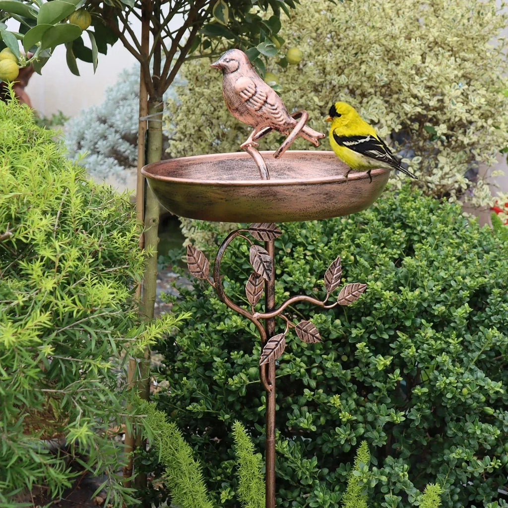 Decorative metal bird bath with birds on a garden background