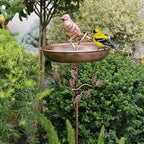 Decorative metal bird bath with birds on a garden background