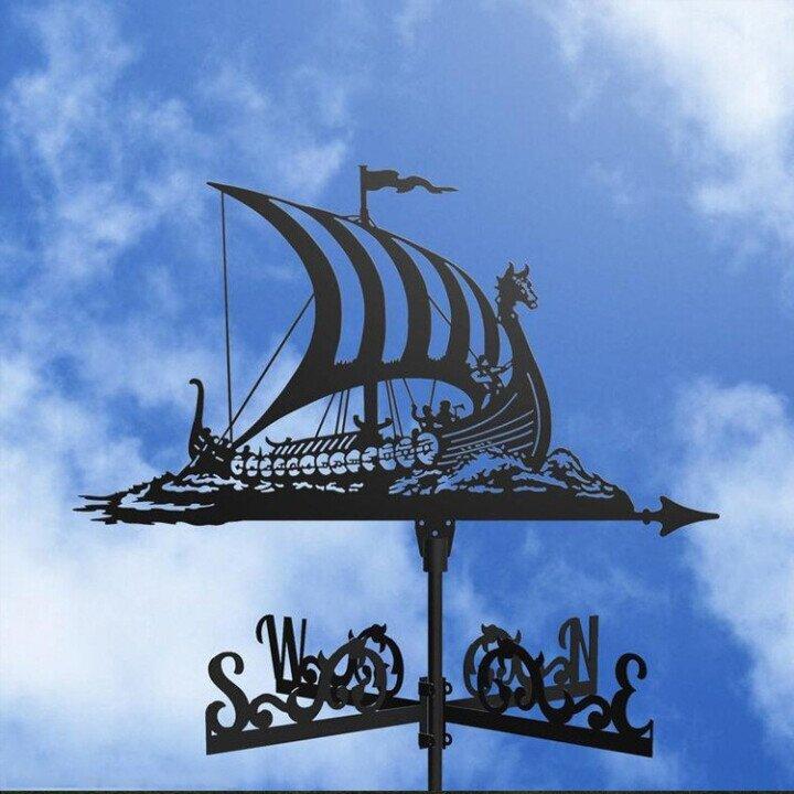 Viking ship weathervane against a blue sky with clouds