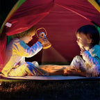 Two children playing with a flashlight inside a colorful tent at night.
