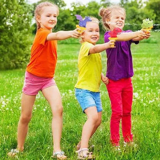 Three children playing with water guns in a grassy field