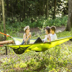 Three people in a green hammock in a forest setting