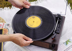 Person placing a vinyl record on a turntable outdoors.