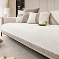 Beige sofa with patterned cushions and a cup on a coffee table in a living room setting.