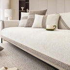 Beige sofa with patterned cushions and a cup on a coffee table in a living room setting.