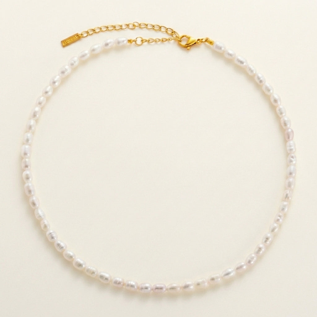 Pearl necklace with a gold clasp on a light beige background