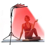 Woman in a yoga pose with a red light therapy lamp on a white background