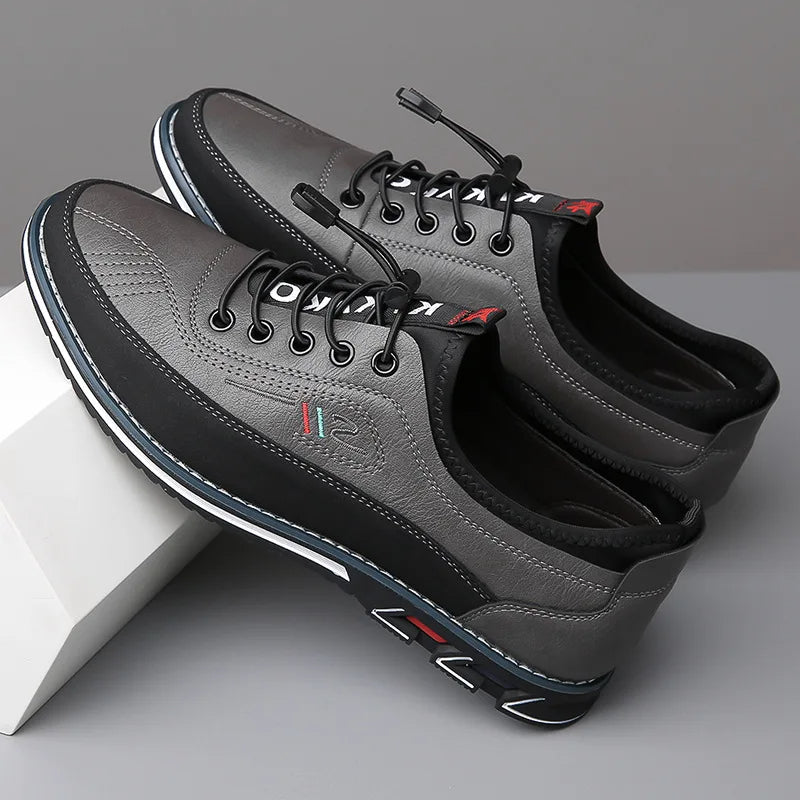 Pair of gray leather shoes with black soles on a light gray background