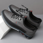 Pair of gray leather shoes with black soles on a light gray background