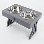 Pet feeding station with two stainless steel bowls on a gray stand.