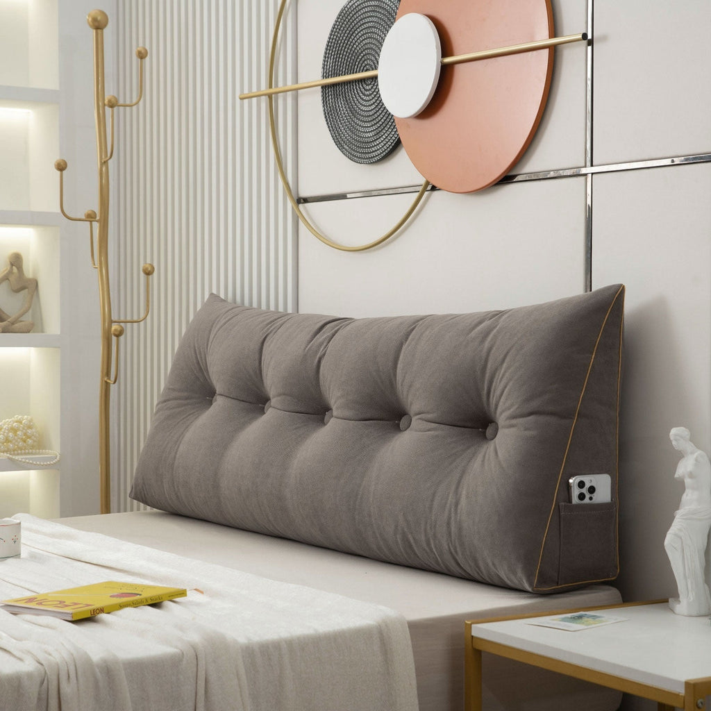 Gray tufted headboard on a bed in a stylish bedroom with decorative wall art.