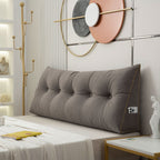 Gray tufted headboard on a bed in a stylish bedroom with decorative wall art.
