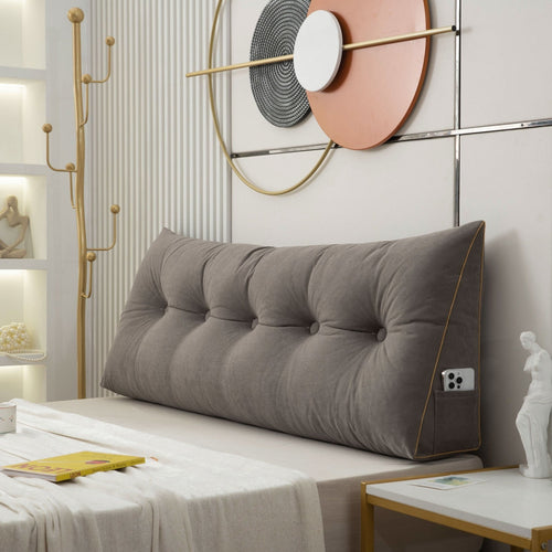 Gray tufted headboard on a bed in a stylish bedroom with decorative wall art.