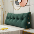 Green tufted headboard pillow on a bed with decorative wall art in the background