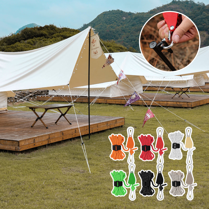 Camping tent with rope management system and color-coded ropes on grassy area with mountains in the background.