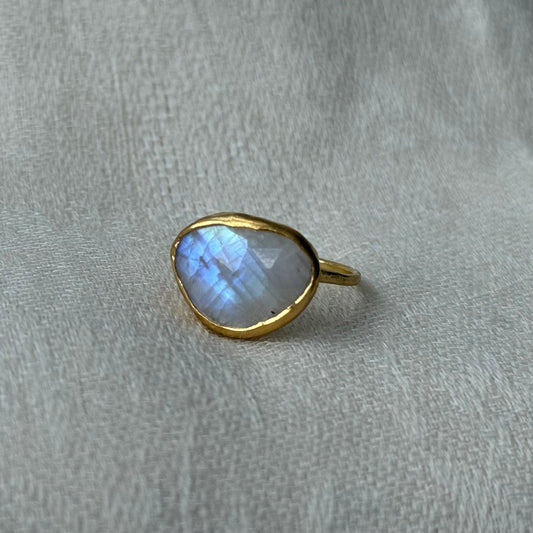 22ct Gold-framed teardrop-shaped Moonstone gemstone on a gray fabric background