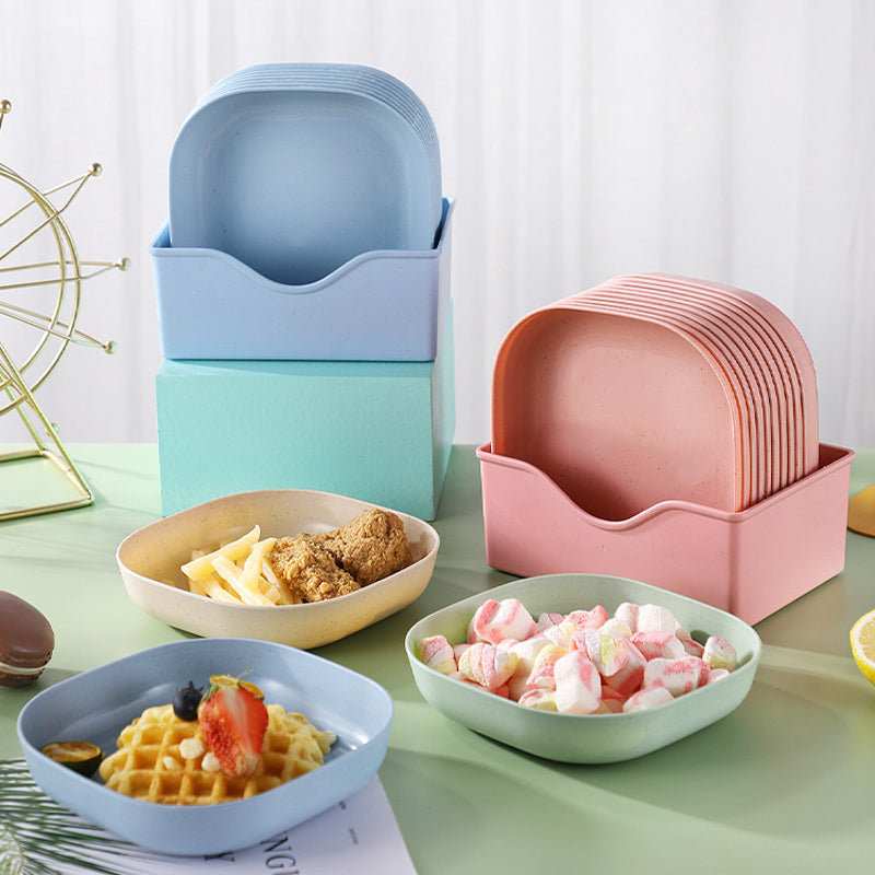 Set of colorful ceramic plates stacked and arranged on a table with food.