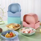 Set of colorful ceramic plates stacked and arranged on a table with food.
