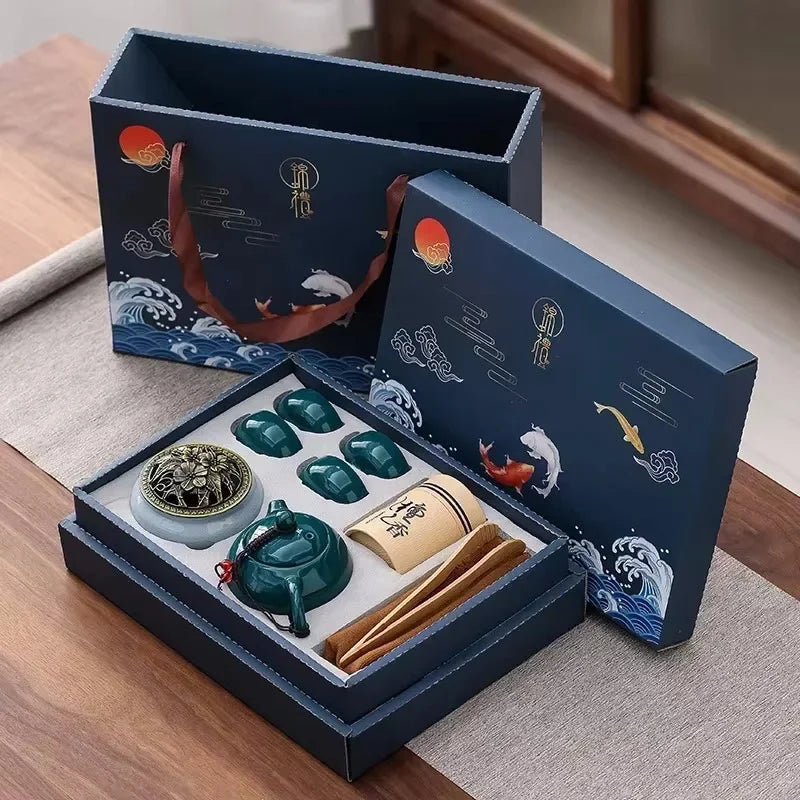Tea set in an open gift box with decorative elements on a wooden surface.