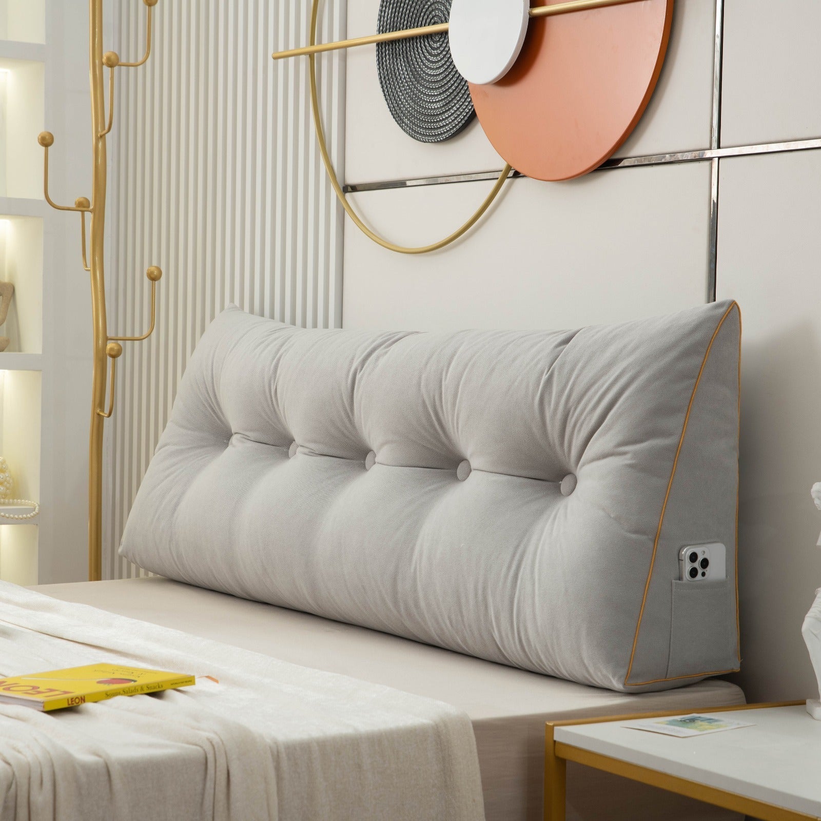 Gray tufted headboard pillow on a bed with decorative wall art in the background