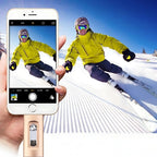 Person skiing with a smartphone camera app displayed on a phone held by a hand.
