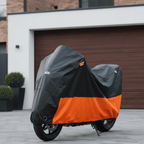 Motorcycle covered with a black and orange cover parked in front of a garage.