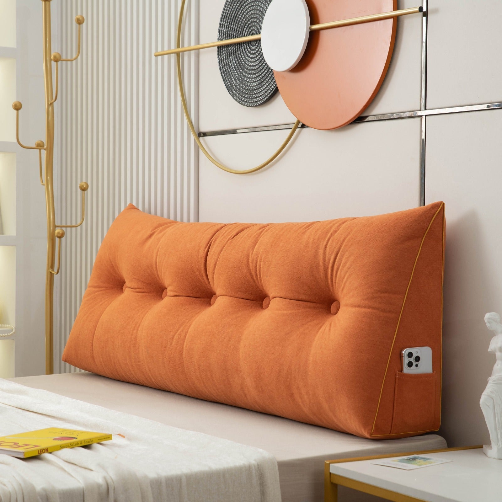 Orange tufted headboard pillow on a bed with decorative elements in the background