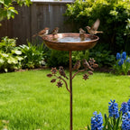 Copper bird bath with birds in a garden setting