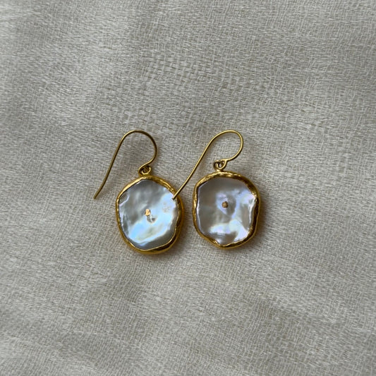22ct Gold-framed pearl earrings on a gray fabric background