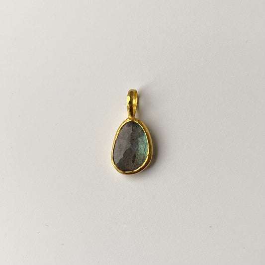 Pendant with a 22ct gold pendant featuring a Labradorite gemstone on a light gray background. Designer is Ram Rijal.