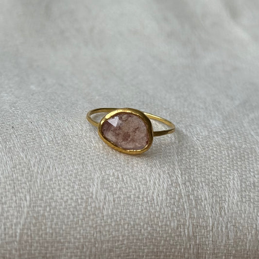 22ct Gold ring with a pink sapphire on a light fabric background