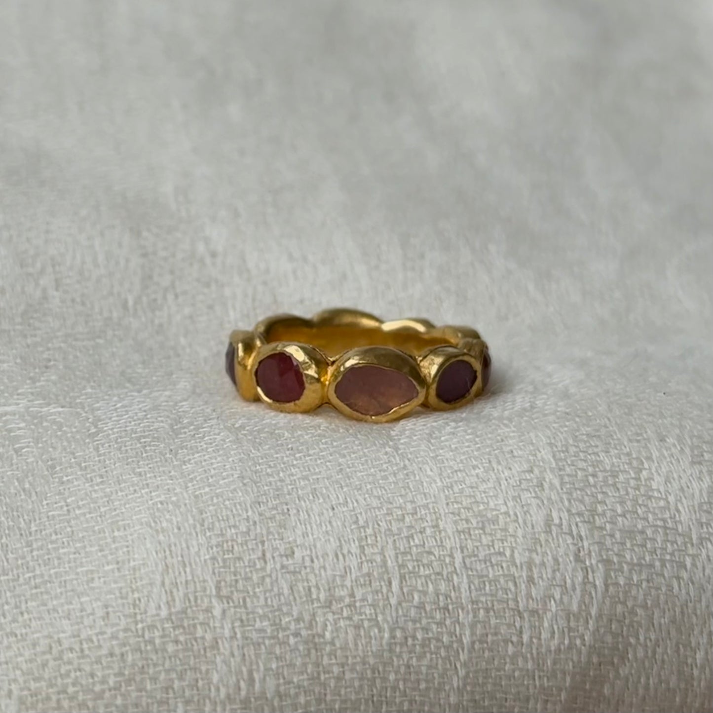 22ct Gold ring with Pink Tourmaline gems on a textured gray background