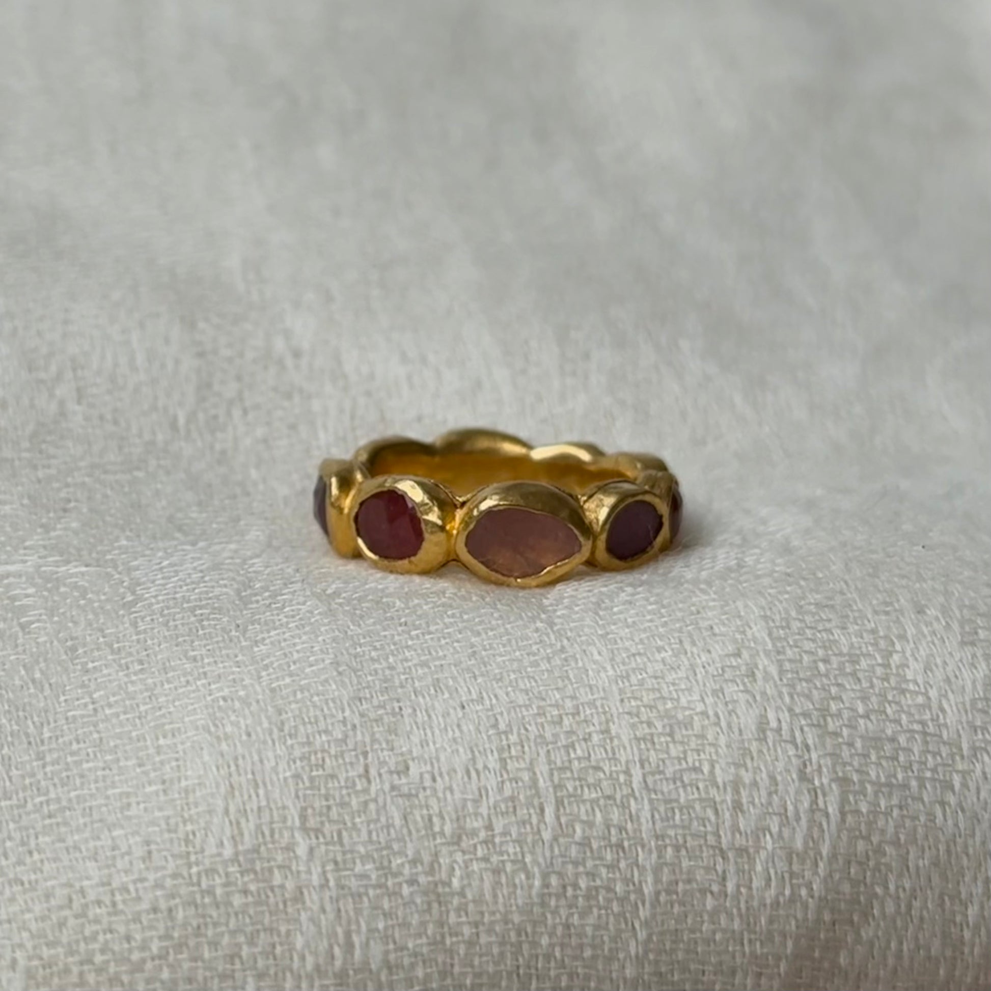 22ct Gold ring with Pink Tourmaline gems on a textured gray background
