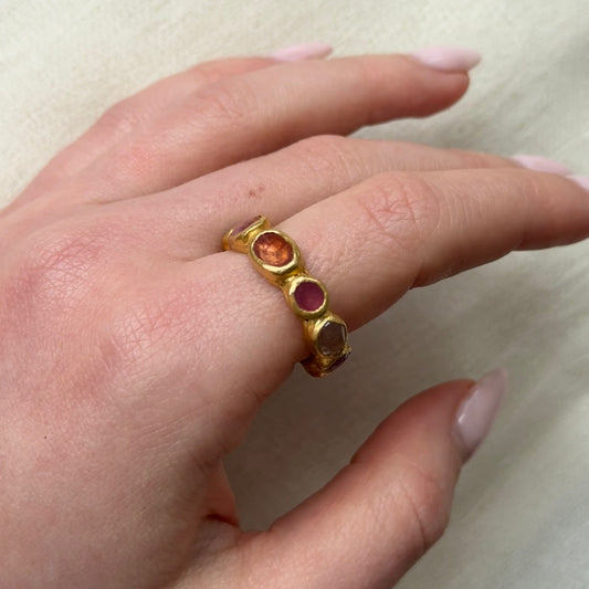22ct Gold ring with embedded Pink Tourmaline gems on a hand against a neutral background