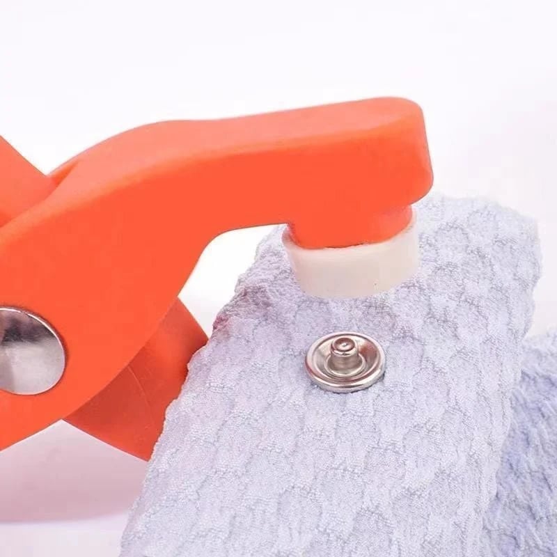 Orange tool pressing a button on a gray fabric background