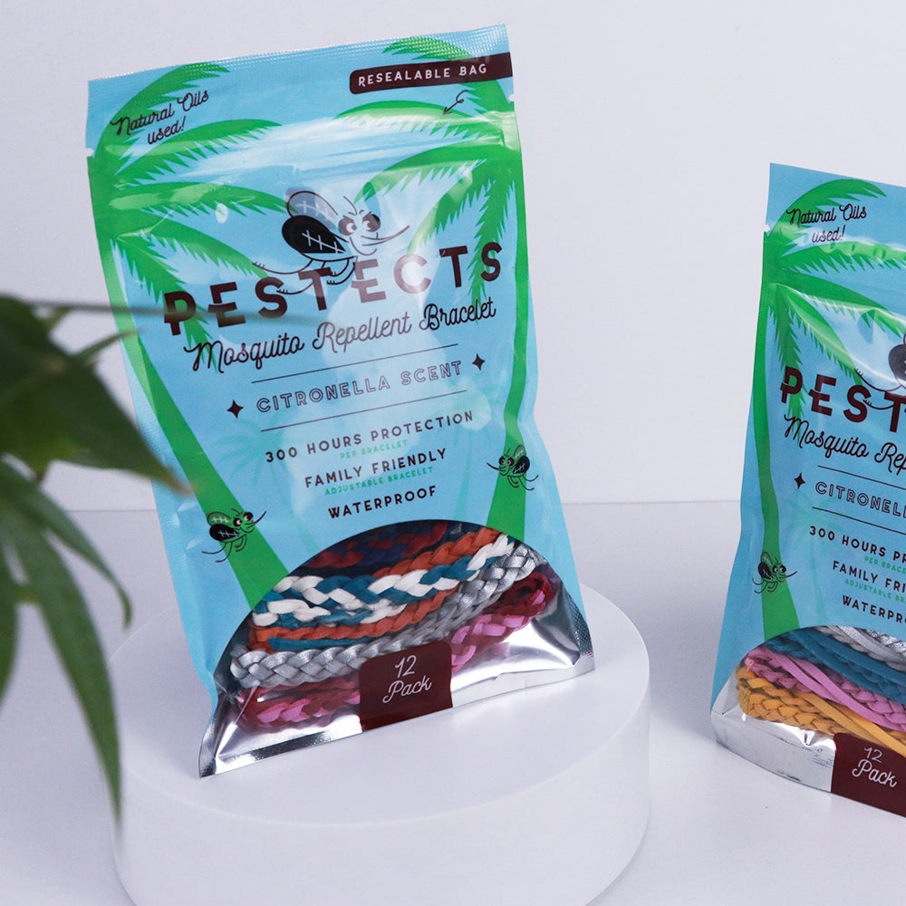 Two packages of Pestects mosquito repellent bracelets on a white background with a plant to the left.