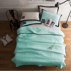 Teal bedspread with black piping on a bed in a bedroom setting.