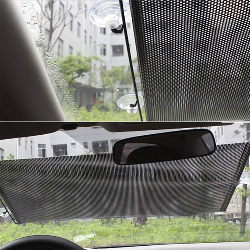 Car sunshade covering a car window with a view of buildings and trees outside.