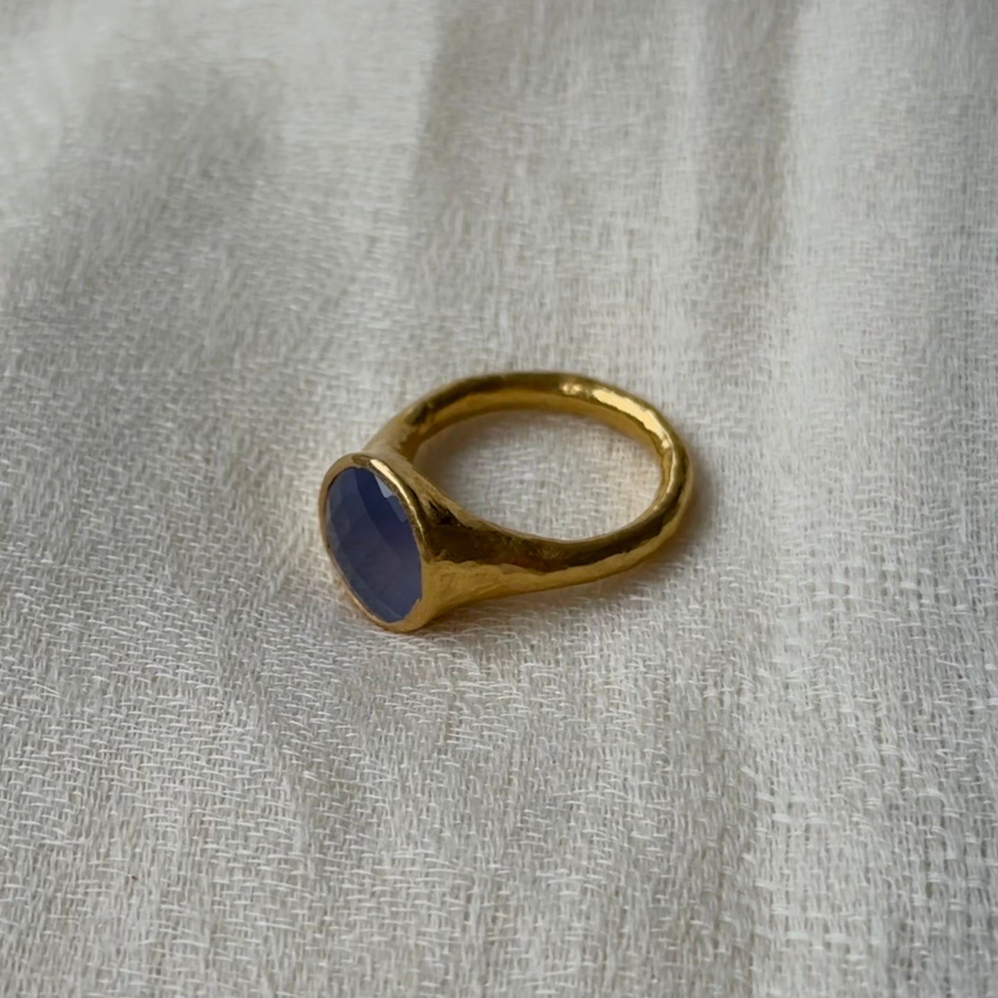 22ct Gold ring with a blue stone on a gray fabric background