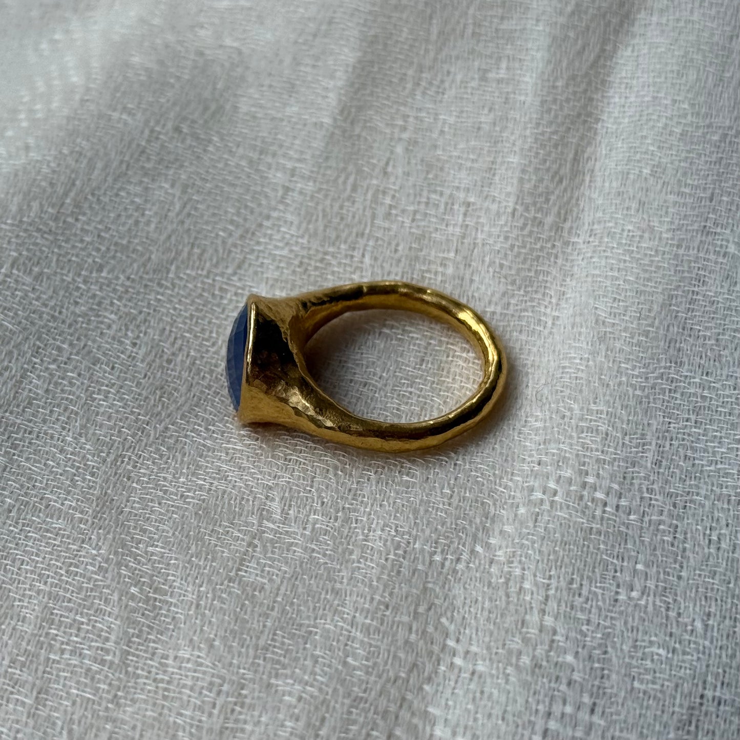 22ct Gold ring with a blue stone on a grey fabric background