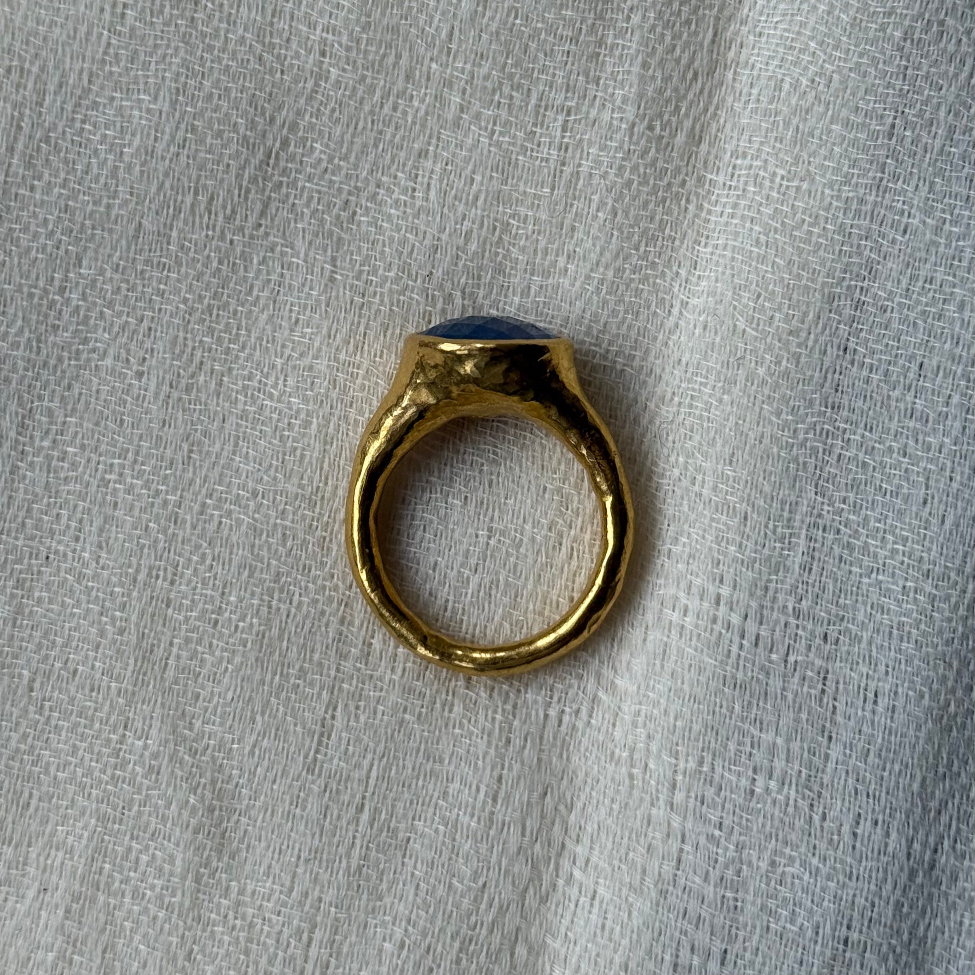 22ct Gold ring with a blue stone on a grey fabric background