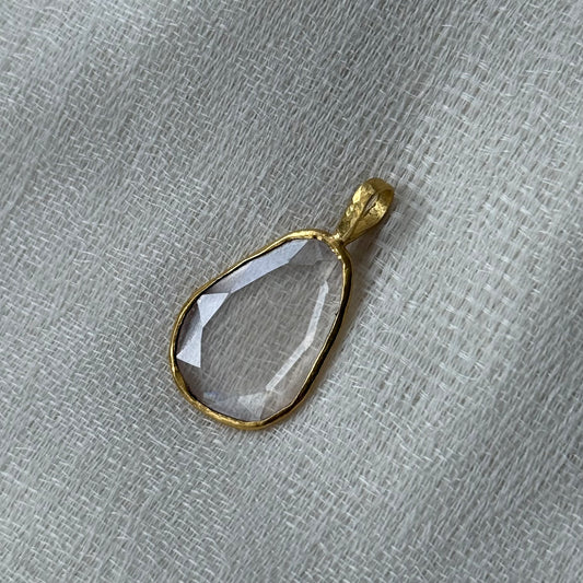 22ct Gold pendant with a clear lab grown diamond on a textured gray background