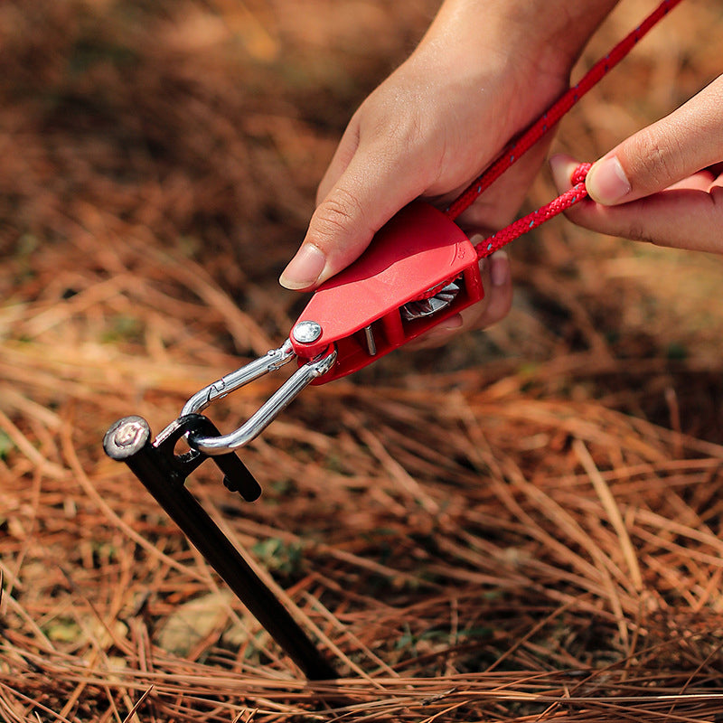 Person using a red battery jump starter on a grassy background
